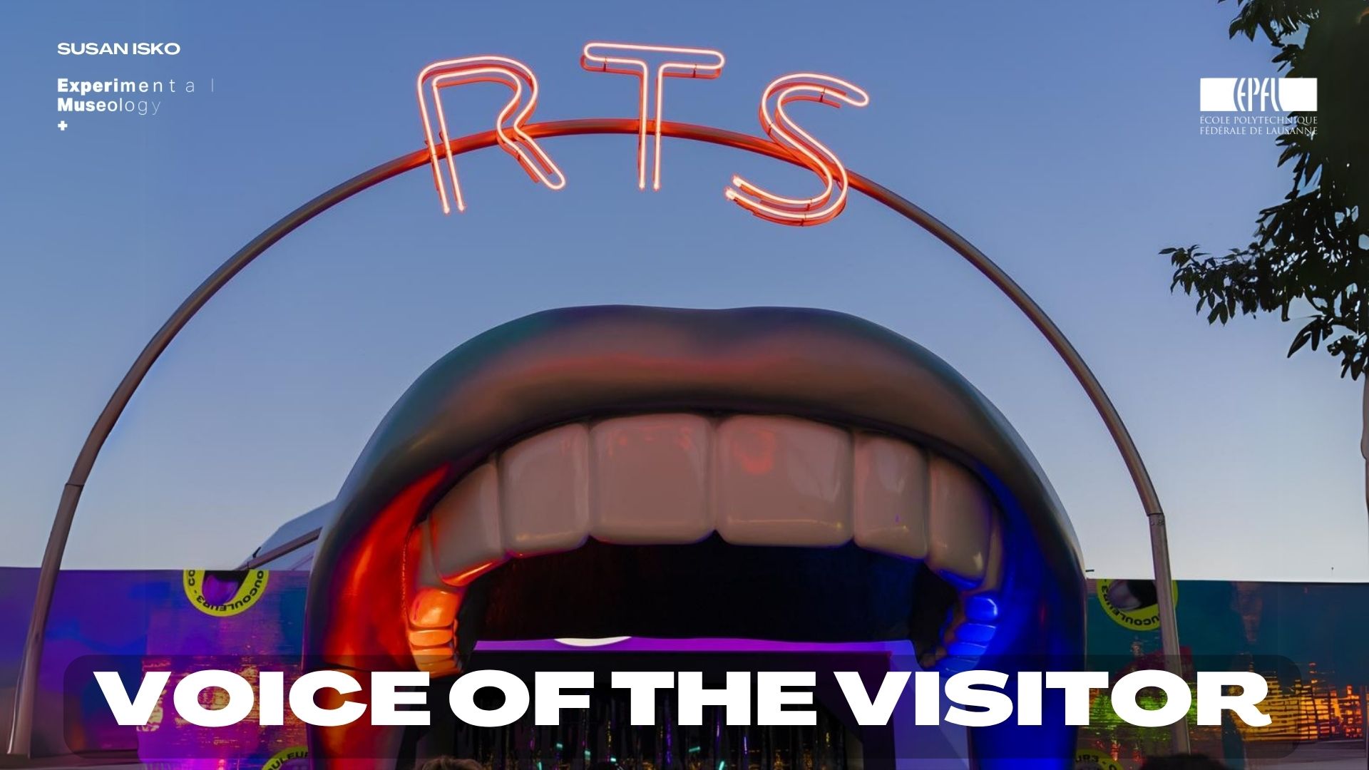 Voice of the Visitor — giant illuminated mouth pavilion under an RTS neon arch at dusk
