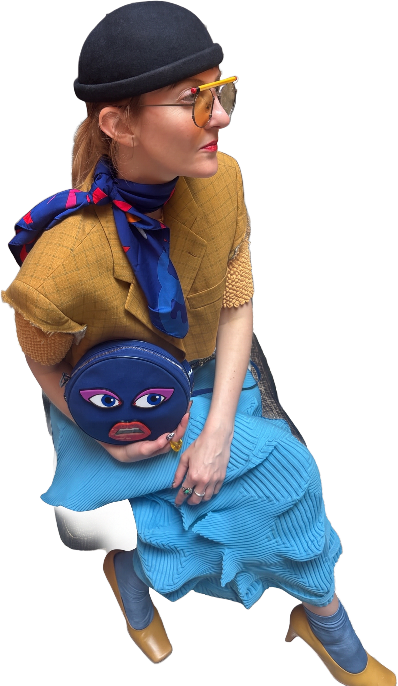 Mustard checked jacket, blue scarf and pleated skirt with a face-print bag